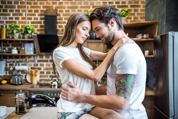 Pareja abrazando en cocina Imágenes De Stock Sin Royalties Gratis