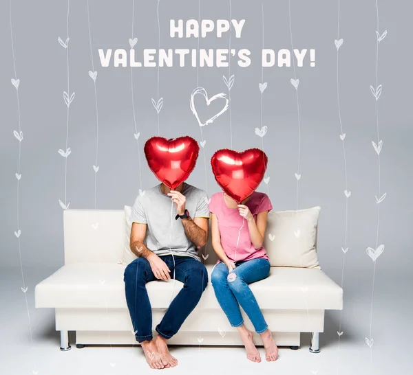 Couple sitting on couch with red balloons Stock Photo