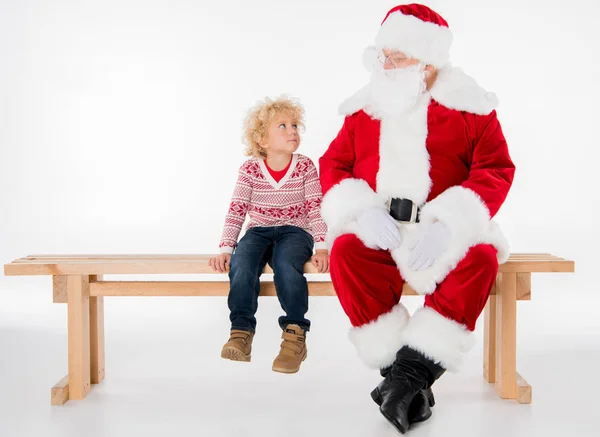 Papá Noel con niño sentado en el banco - foto de stock