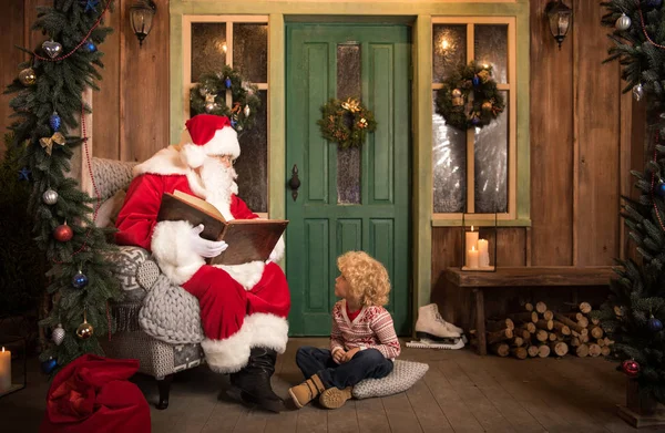Santa Claus reading book to kid — Stock Photo