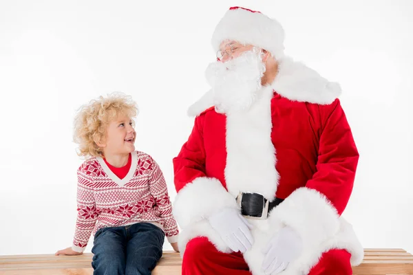 Санта-Клаус с ребенком, сидящим на скамейке — стоковое фото