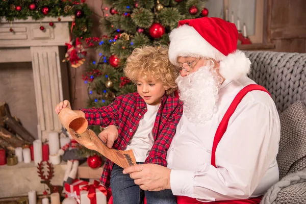Santa Claus y niños leyendo la lista de deseos - foto de stock