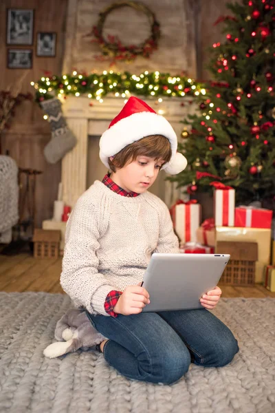 Bambino in cappello Babbo Natale con tablet digitale — Foto stock
