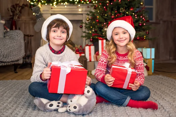 Kinder in Weihnachtsmützen mit Weihnachtsgeschenken — Stockfoto