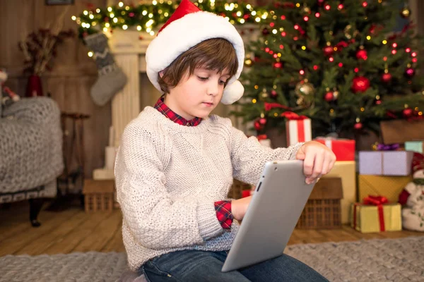 Bambino in cappello Babbo Natale con tablet digitale — Foto stock