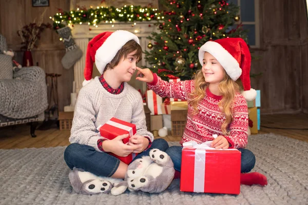 Kinder in Weihnachtsmützen mit Weihnachtsgeschenken — Stockfoto