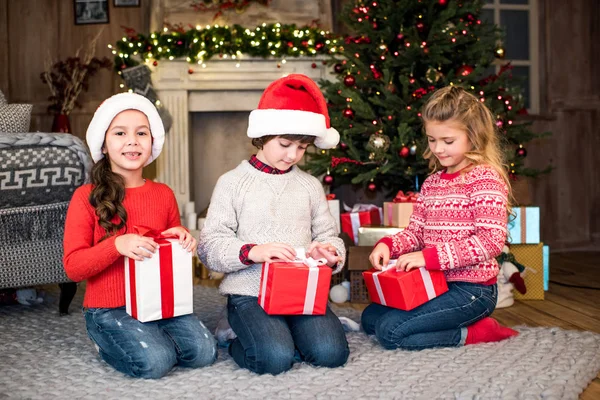 Enfants en chapeaux de Père Noël avec des boîtes-cadeaux — Photo de stock