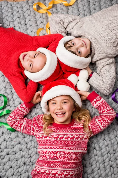 Bambini in cappelli Babbo Natale sdraiati in cerchio — Foto stock