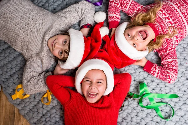 Діти в Санта-капелюхах лежать в колі — стокове фото