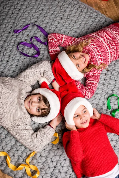 Bambini in cappelli Babbo Natale sdraiati in cerchio — Foto stock