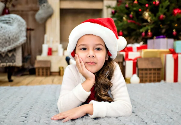 Miúdo de chapéu de Pai Natal deitado no tapete — Fotografia de Stock