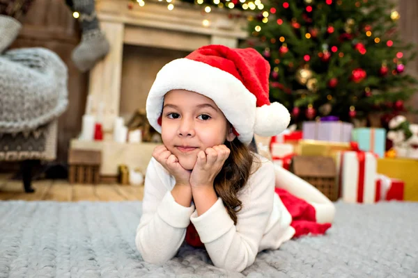 Bambino in cappello Babbo Natale sdraiato su tappeto — Foto stock