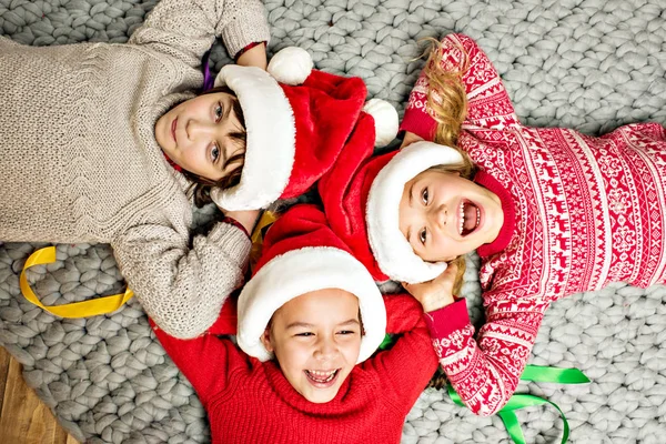 Діти в Санта-капелюхах лежать в колі — стокове фото