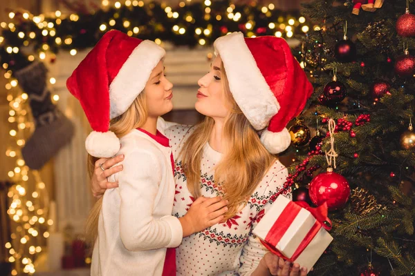 Happy mother and daughter in santa hats — Stock Photo
