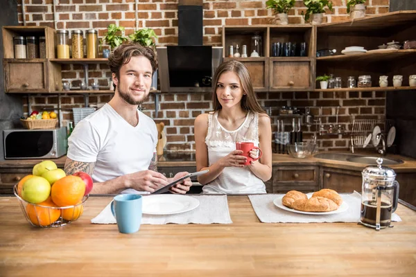 Pareja usando tableta digital en la cocina - foto de stock