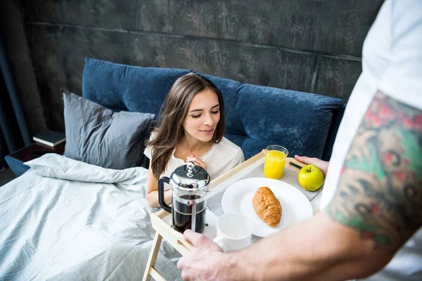 Man brings breakfast in bed — Stock Photo