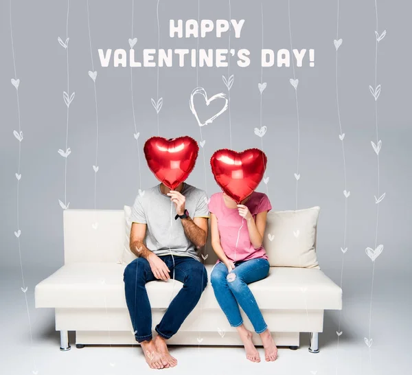 Couple assis sur le canapé avec des ballons rouges — Photo de stock