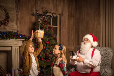 Santa Claus with children using hexacopter drone  clipart