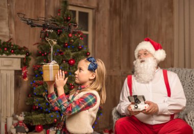 Santa with kid using hexacopter drone clipart