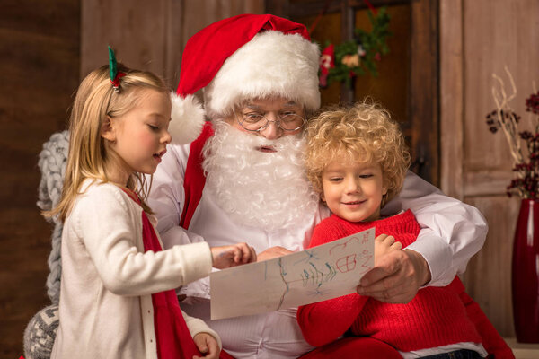 Дети показывают картинку Санта-Клаусу
 