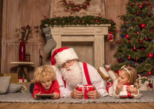 Santa Claus and children lying on carpet