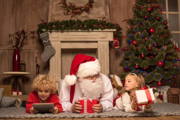 Santa Claus and children lying on carpet