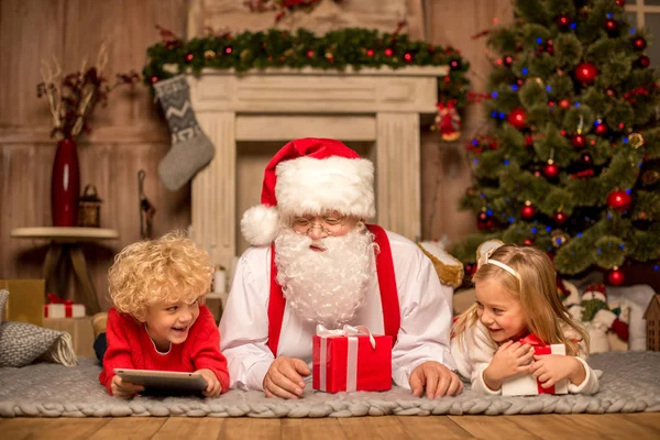 Jultomten och barn liggande på matta — Stockfoto