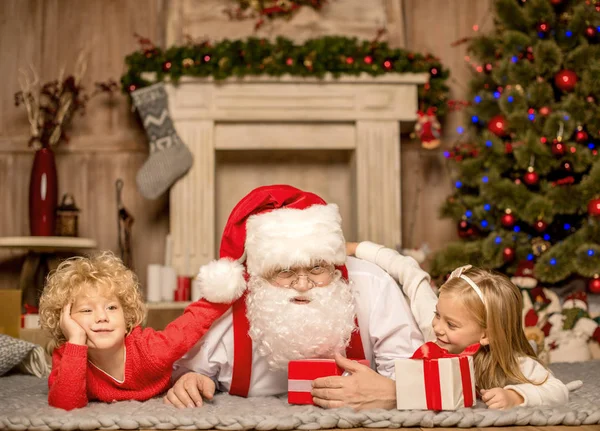 Jultomten och barn liggande på matta — Stockfoto