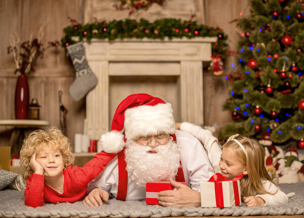 Santa Claus and children lying on carpet