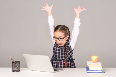 Schoolgirl at desk with laptop clipart