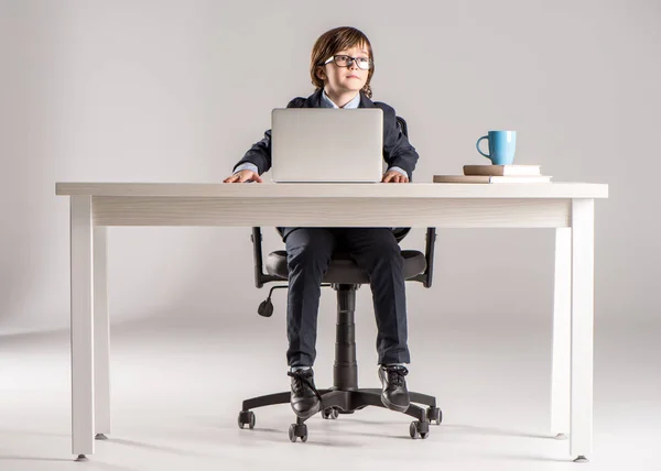 Écolier en costume d'affaires assis travaillant avec un ordinateur portable — Photo