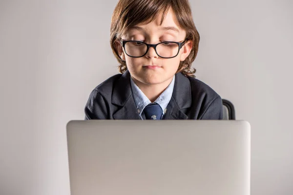 Schoolchild in business suit using laptop — Stock Photo, Image