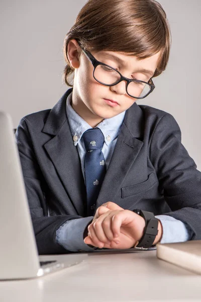 Schulkind im Businessanzug schaut auf Smartwatch — Stockfoto
