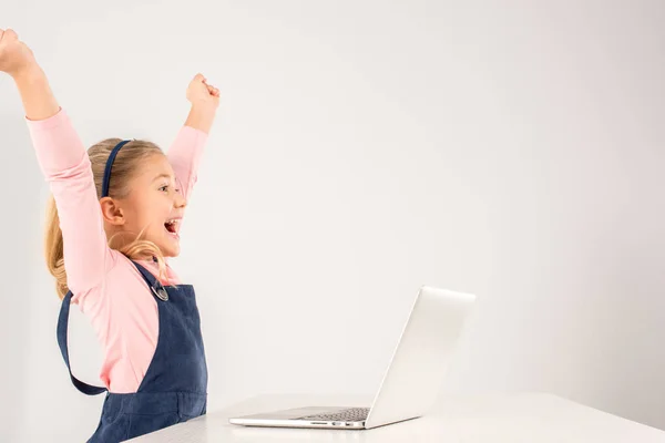 Schoolmeisje aan balie met laptop — Stockfoto