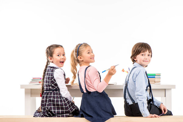 Smiling schoolchildren sitting at desk