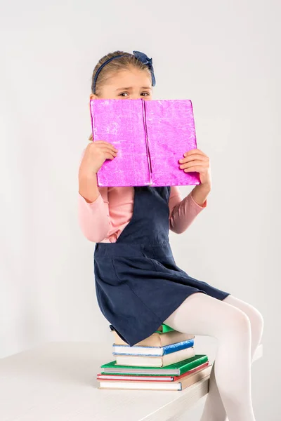 Schoolgirl sitting on pile of books — Free Stock Photo