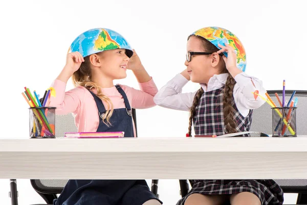 Schoolgirls with halves of globe on heads — Stock Photo, Image