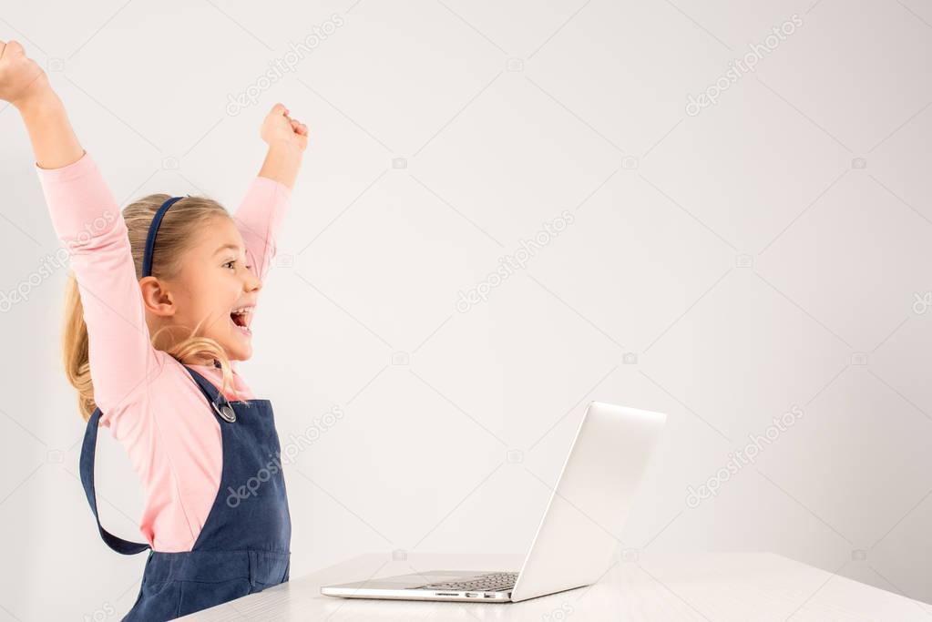 Schoolgirl at desk with laptop