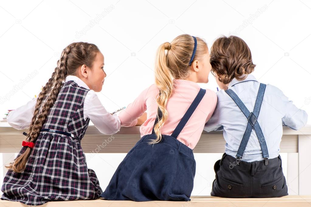 Schoolchildren sitting at desk and talking