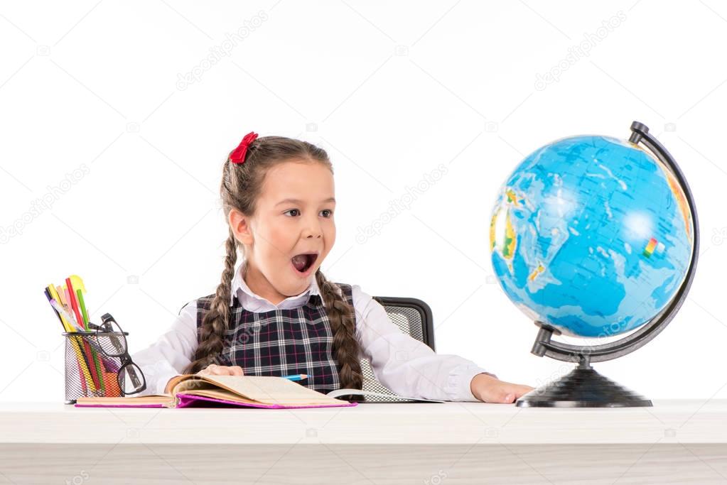 Shocked schoolgirl looking at globe  