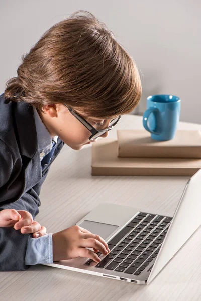 Schoolchild in business suit using laptop computer — Stock Photo, Image