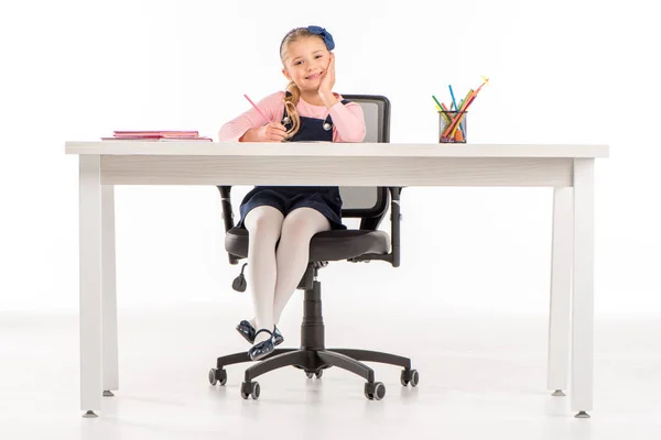 Lachende schoolmeisje zit aan bureau met boeken — Stockfoto