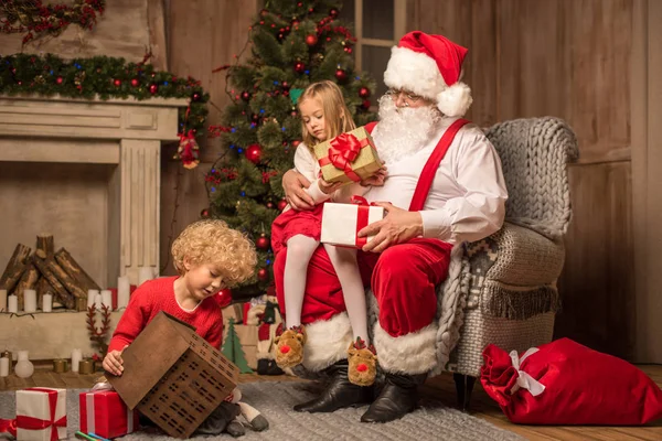 Papai Noel com crianças sentadas perto da lareira — Fotografia de Stock