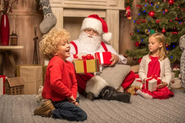 Santa Claus and children with Christmas gifts — Stock Photo