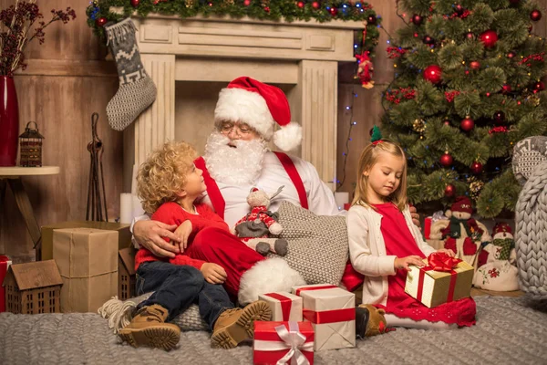 Weihnachtsmann und Kinder mit Weihnachtsgeschenken — Stockfoto