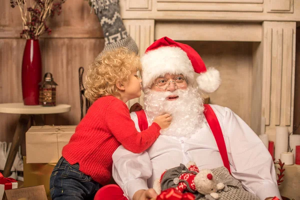 Kind flüstert dem Weihnachtsmann einen Wunsch zu — Stockfoto