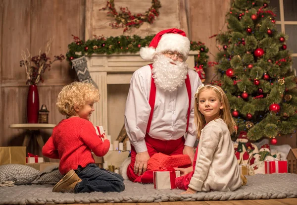 Santa Claus and children with Christmas gifts — Stock Photo