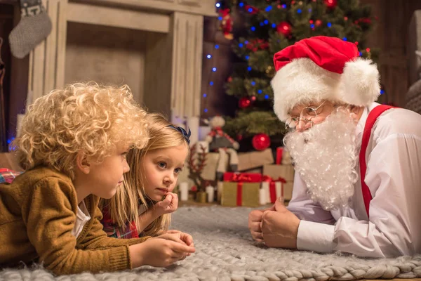 Niños y Papá Noel acostados en la alfombra - foto de stock