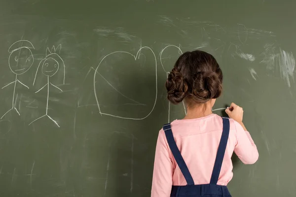 Schoolgirl drawing on blackboard — Stock Photo