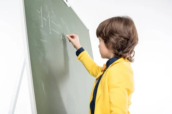 Schoolboy writing on blackboard — Stock Photo